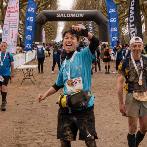 Un jeune homme, portant le maillot inalco, c&eacute;l&egrave;bre sous l'arche de l'arriv&eacute;e