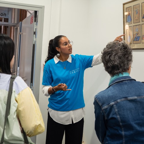 Une étudiante bénévole décrit un tableau à deux visiteurs